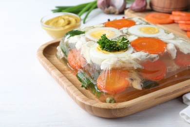 Photo of Delicious fish aspic served on white wooden table, closeup