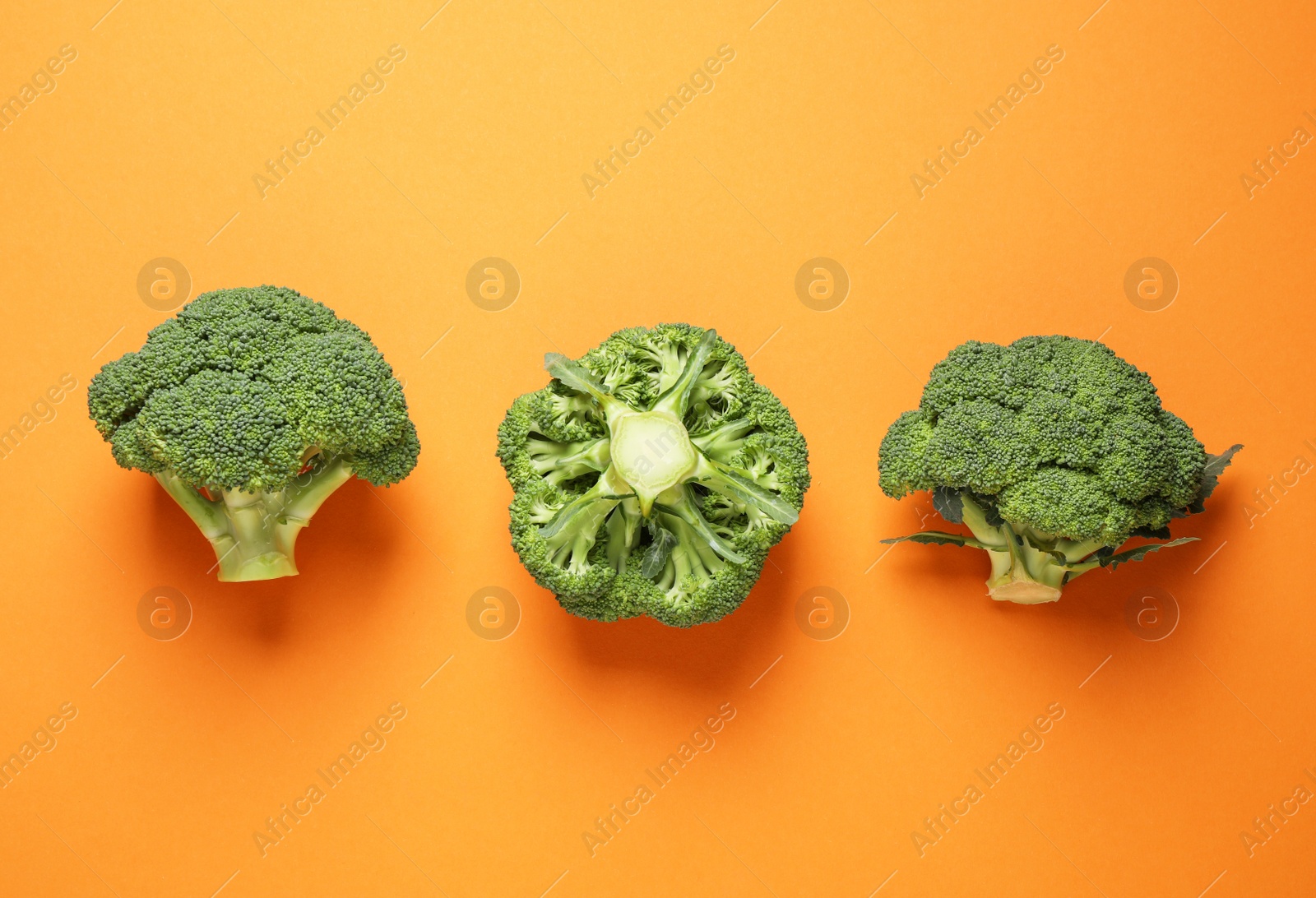 Photo of Fresh tasty broccoli on orange background, flat lay