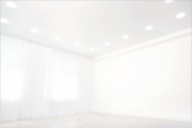 Image of Empty room with windows and white wall, blurred view