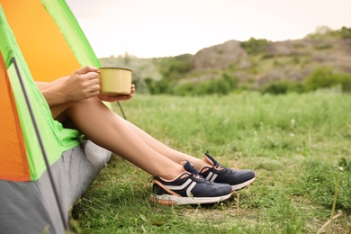 Photo of Young woman with mug resting in camping tent