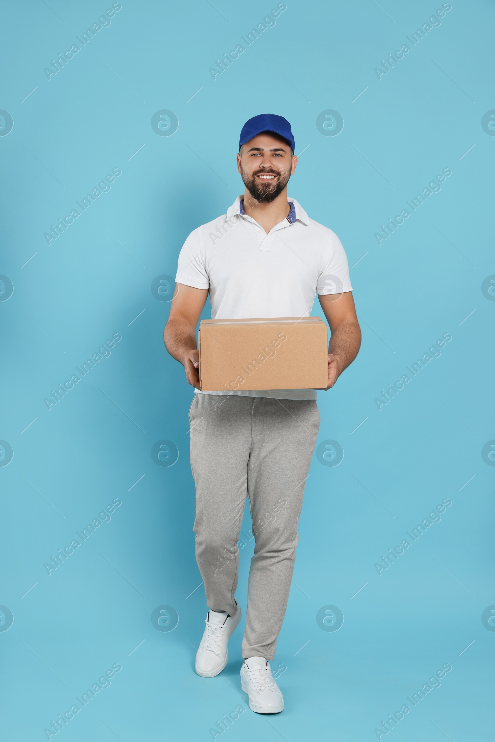 Photo of Courier holding cardboard box on light blue background