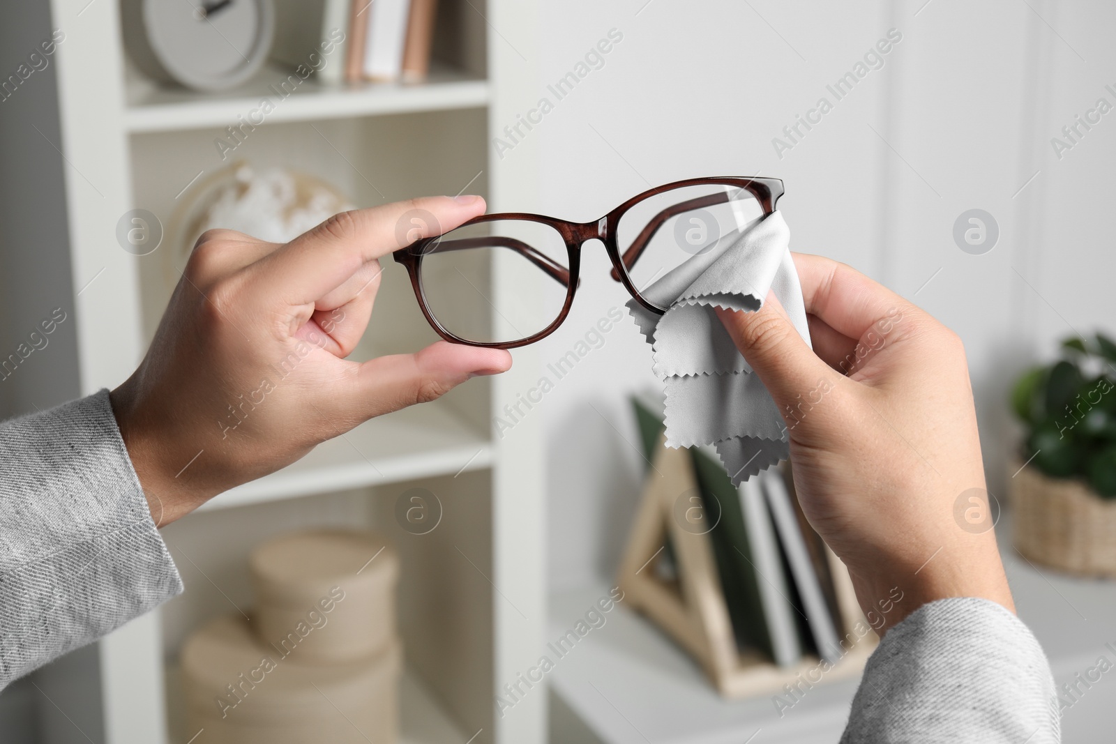 Photo of Man wiping glasses with microfiber cloth indoors, closeup