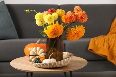 Photo of Beautiful autumn bouquet and pumpkins on coffee table near sofa in room