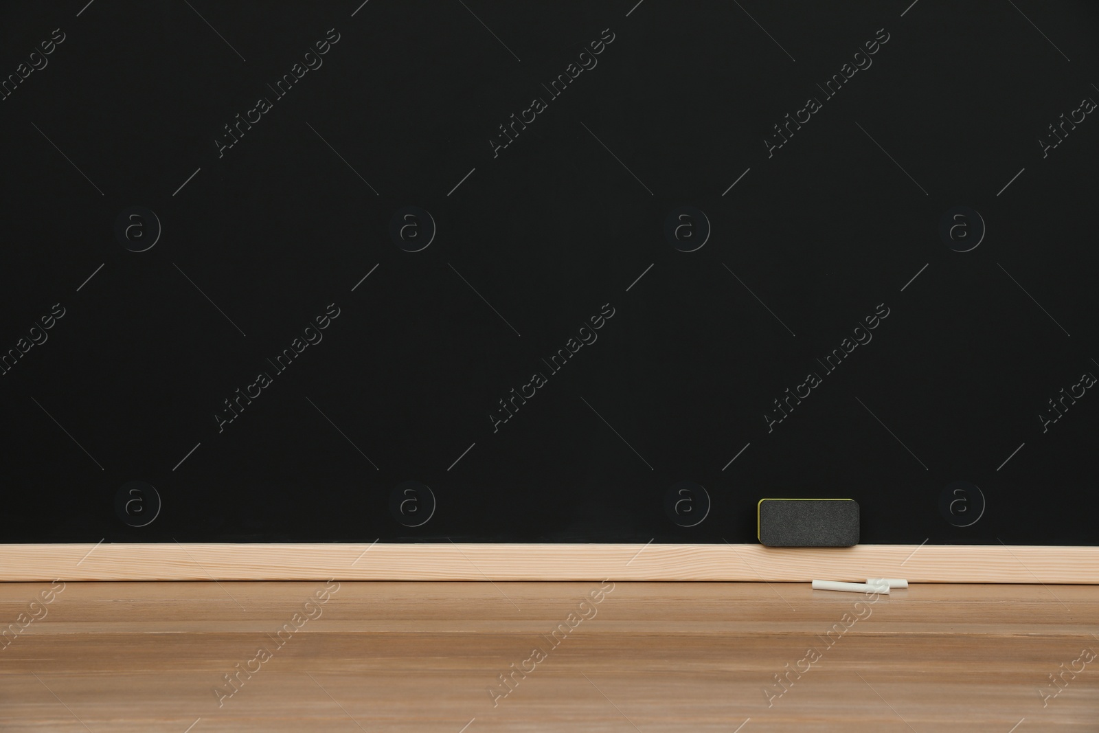 Photo of Pieces of chalk and duster on wooden table near blackboard, space for text
