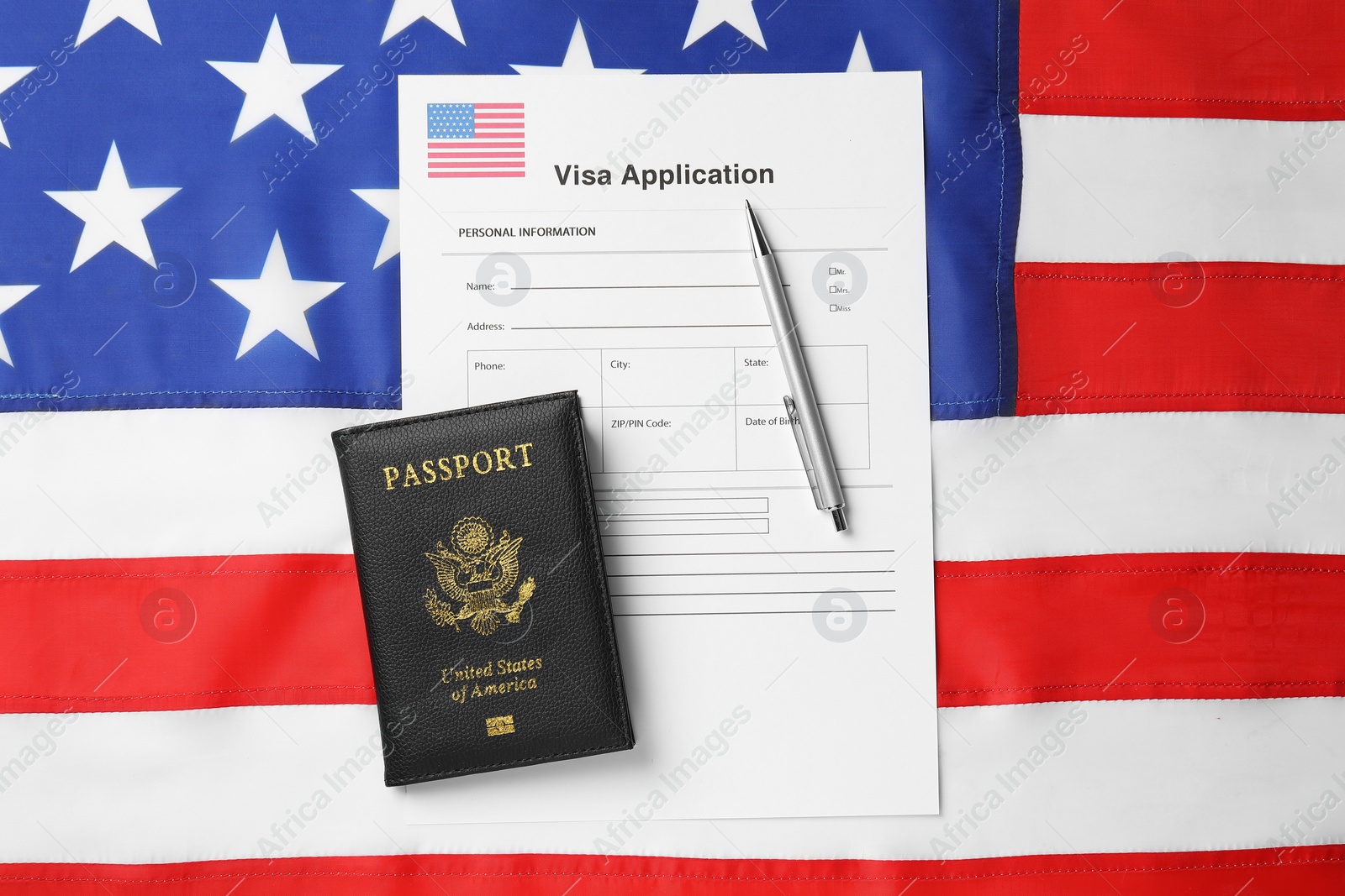 Photo of Immigration to USA. Visa application form, pen and passport on flag, top view
