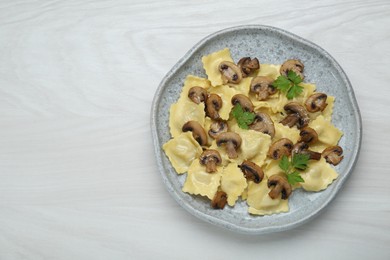 Delicious ravioli with mushrooms on white wooden table, top view. Space for text