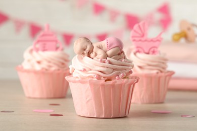 Photo of Beautifully decorated baby shower cupcakes for girl with cream and toppers on wooden table