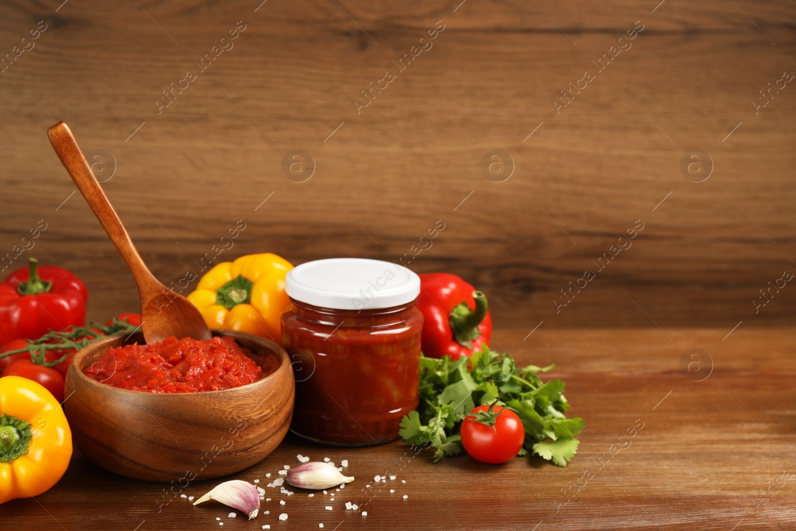 Photo of Delicious lecho and fresh ingredients on wooden table. Space for text
