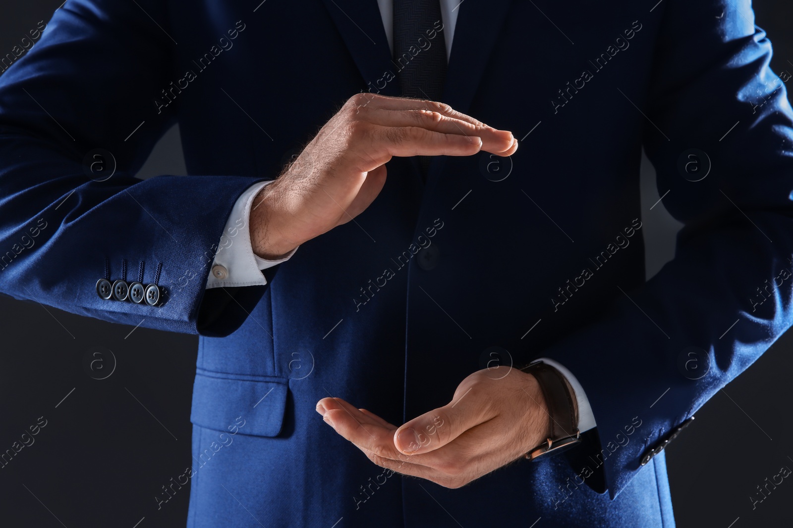 Photo of Businessman holding something in hands on dark background