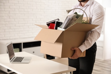 Photo of Young man with box of stuff in office, closeup