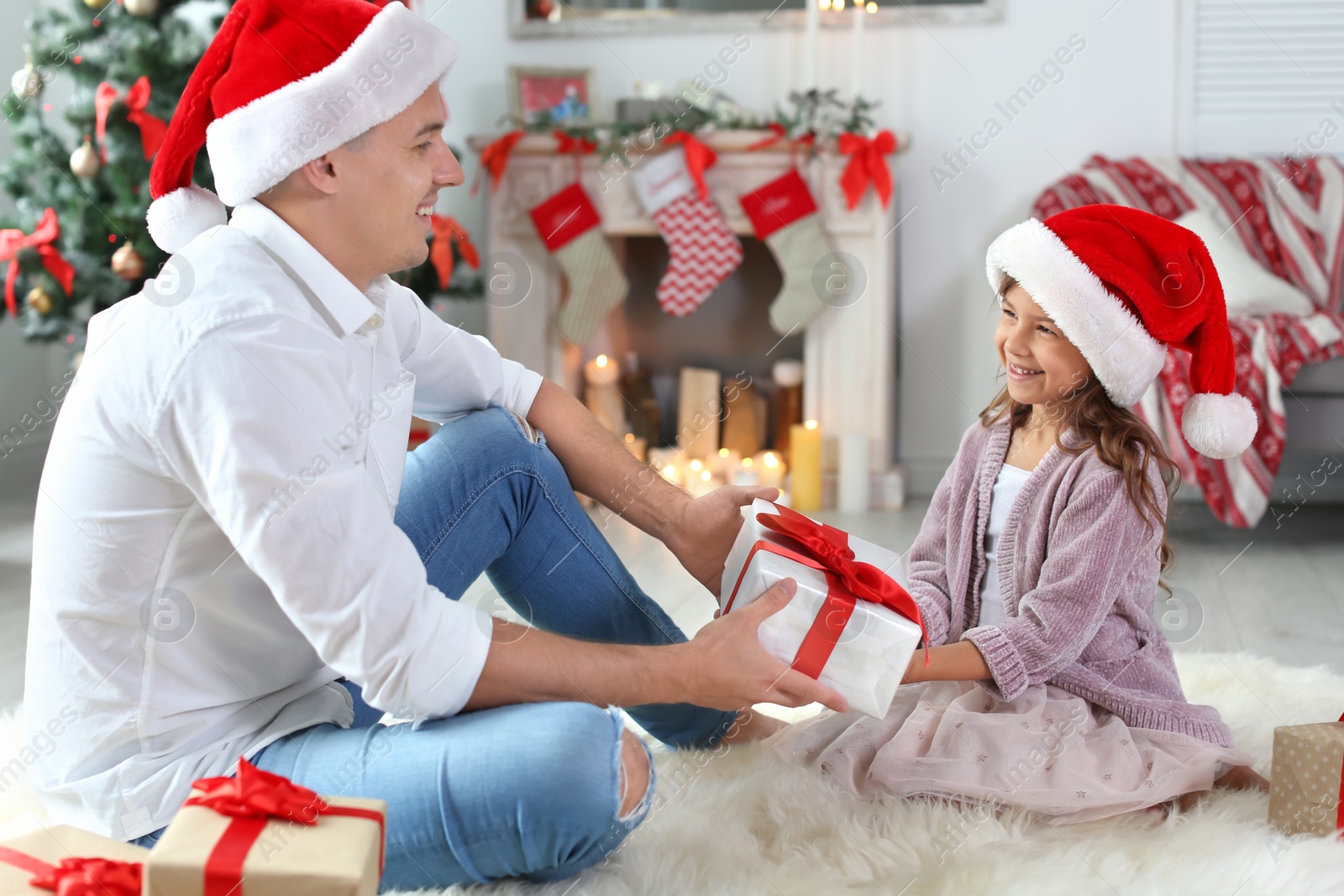 Photo of Father and child in Santa hats with gifts at home. Christmas celebration