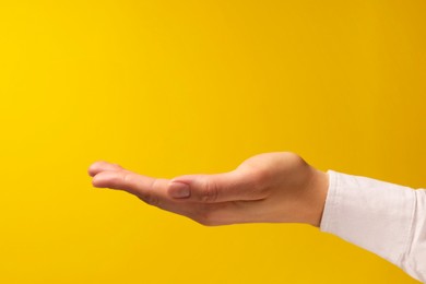 Photo of Woman holding something in hand on yellow background, closeup. Space for text