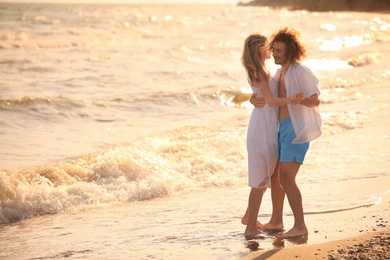 Photo of Young couple dancing on beach at sunset