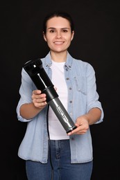 Photo of Beautiful young woman holding sous vide cooker on black background