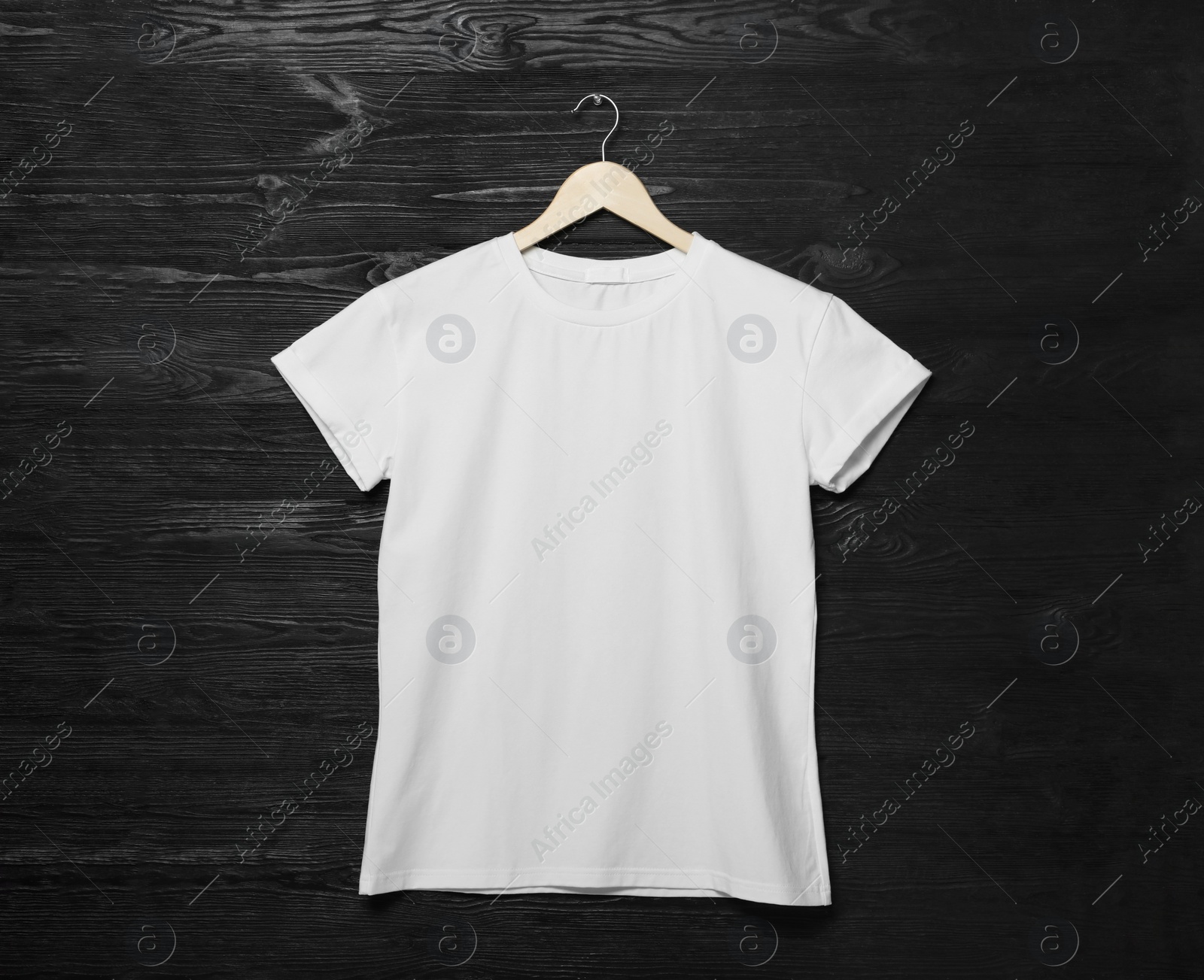 Photo of Hanger with stylish white T-shirt on black wooden wall