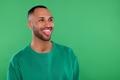 Photo of Happy young man showing his tongue on green background, space for text