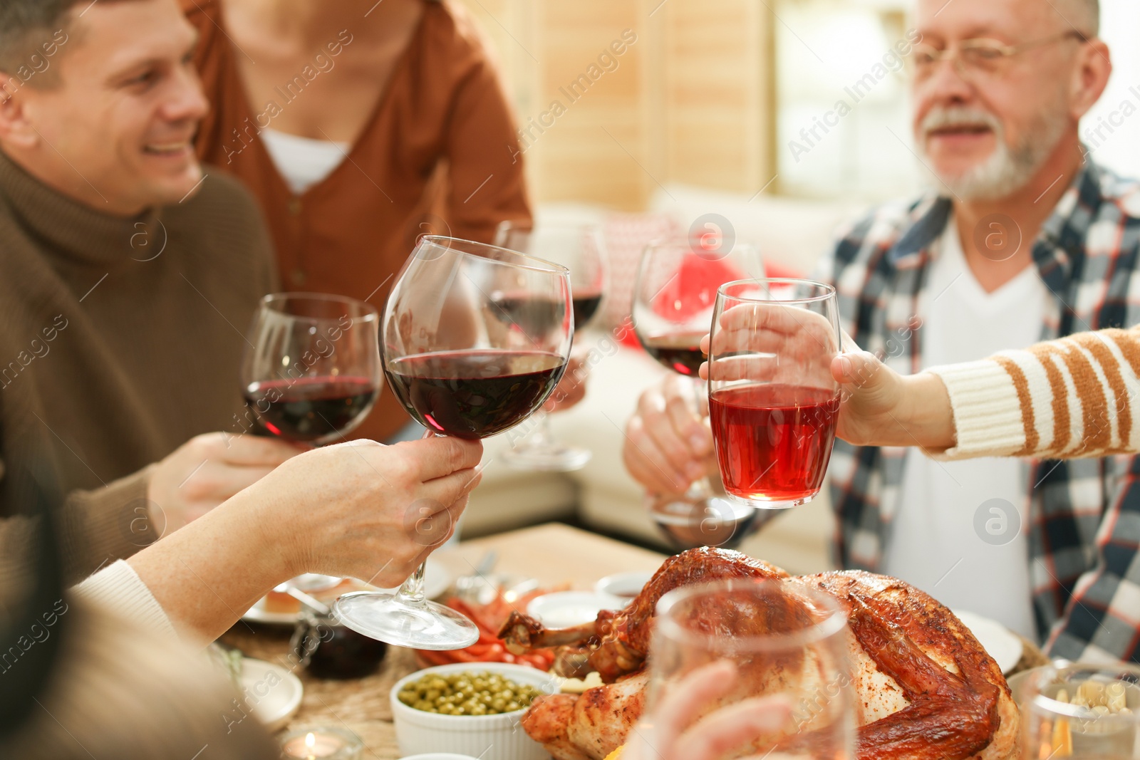 Photo of Family clinking glasses of drinks at festive dinner, focus on hands. Christmas celebration