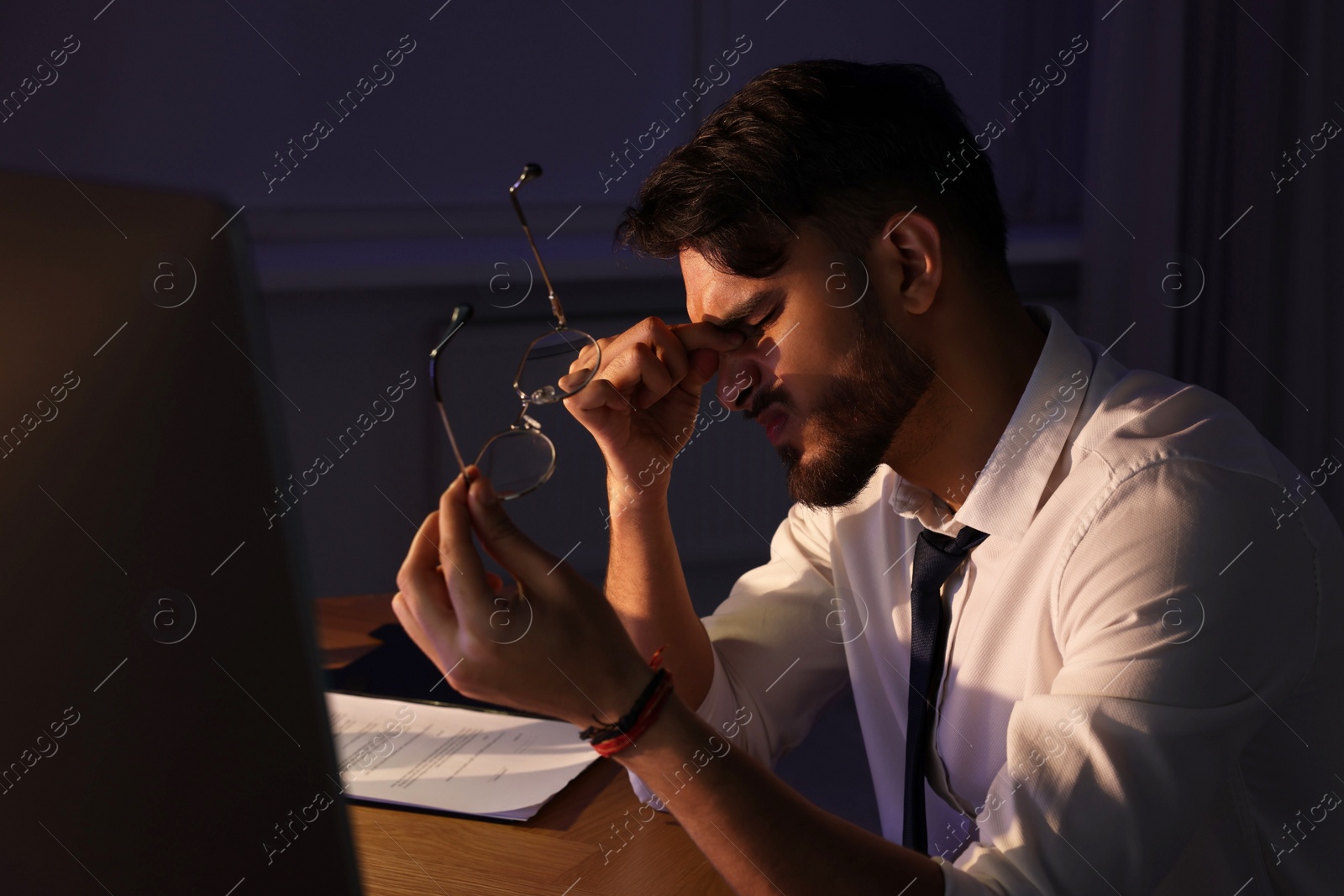 Photo of Tired young man working late in office