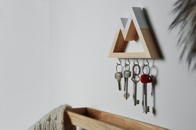 Photo of Wooden key holder on light wall indoors. Space for text