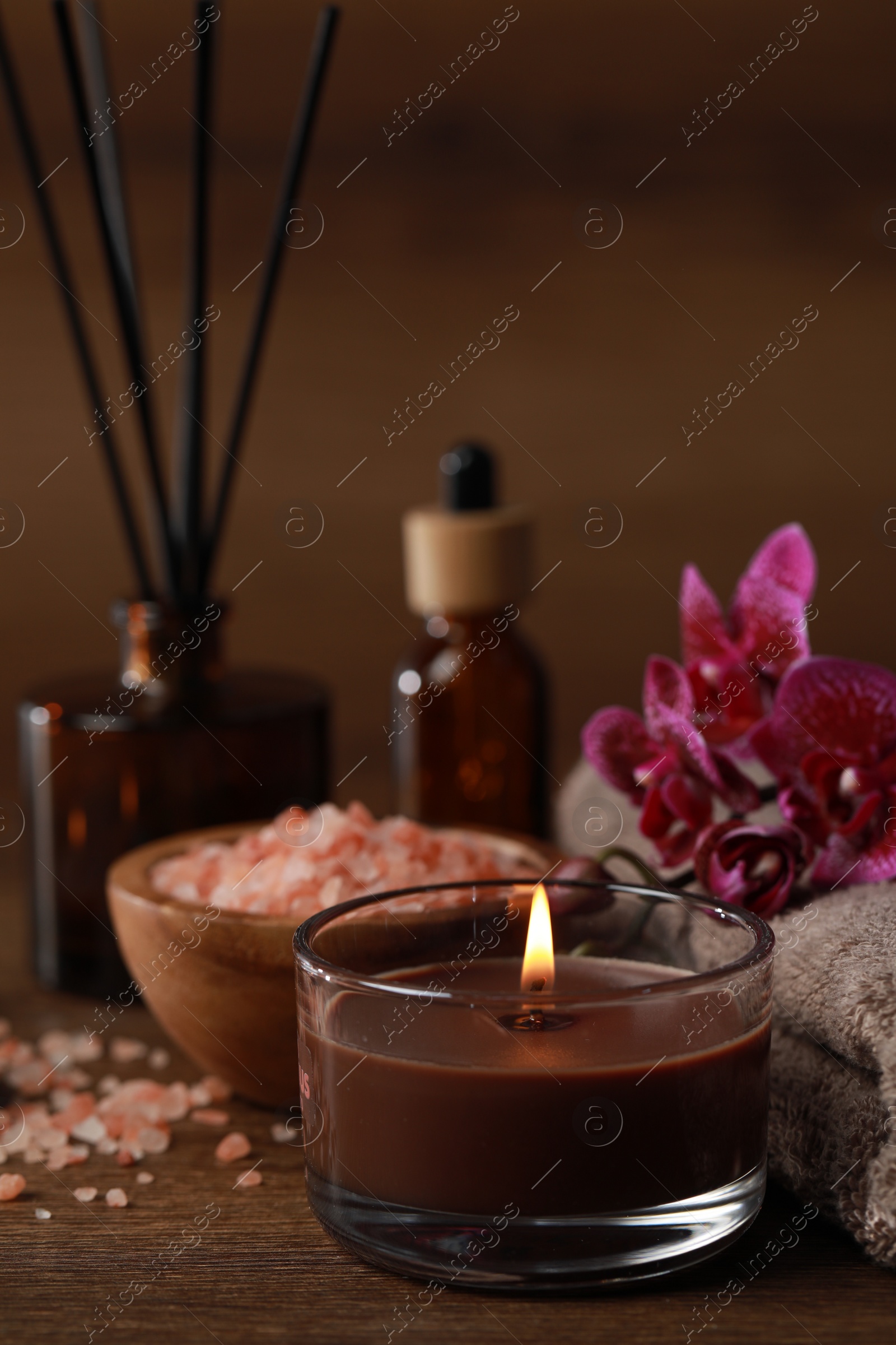 Photo of Beautiful spa composition with burning candle, sea salt and flowers on wooden table
