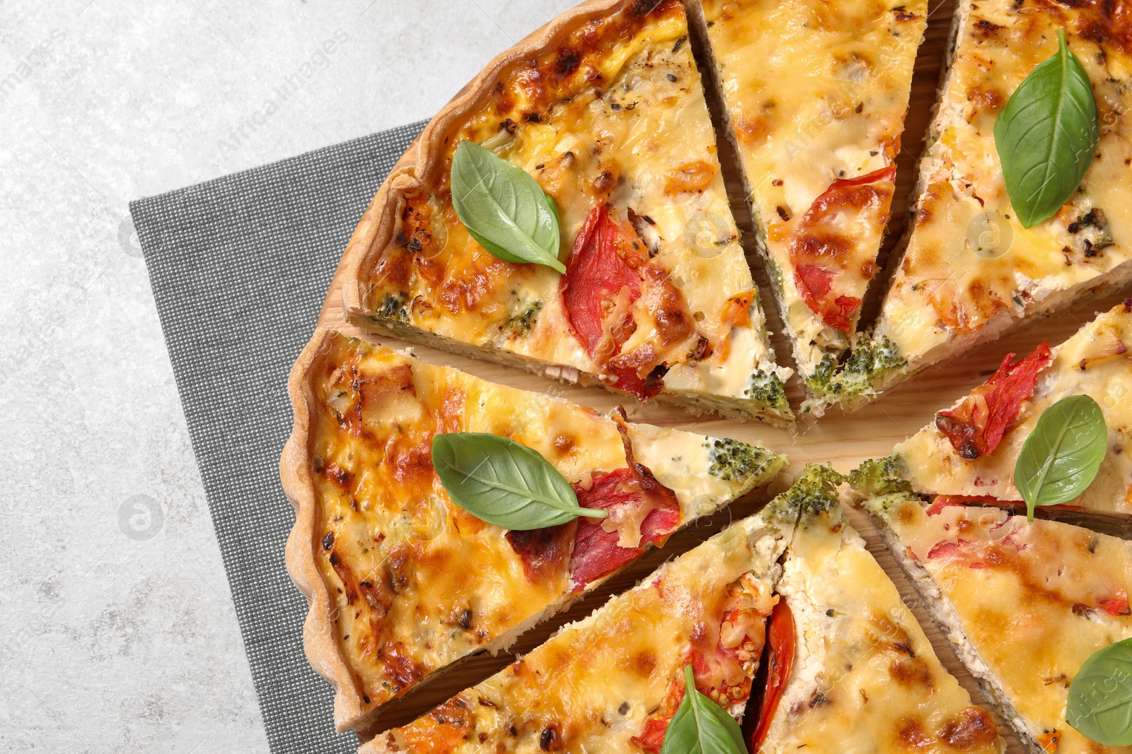 Photo of Tasty quiche with tomatoes, basil and cheese on light textured table, top view