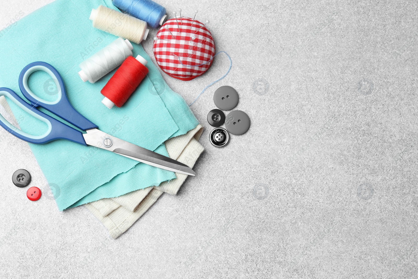 Photo of Flat lay composition with scissors, spools of threads and sewing tools on light background, space for text