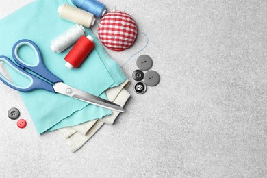 Photo of Flat lay composition with scissors, spools of threads and sewing tools on light background, space for text