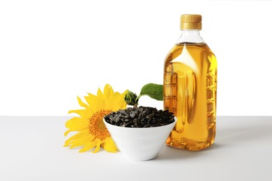 Photo of Bottle of cooking oil, sunflower seeds and flower on white background