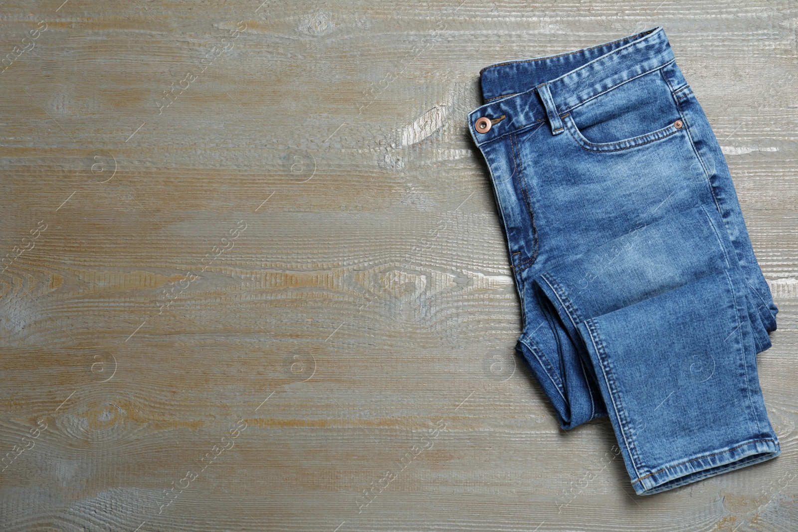 Photo of New stylish jeans on wooden background, top view. Space for text