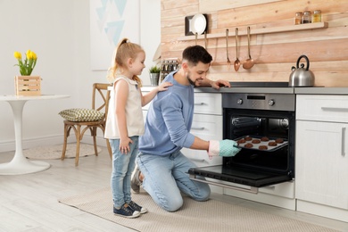 Photo of Father with his daughter baking cookies in oven at home