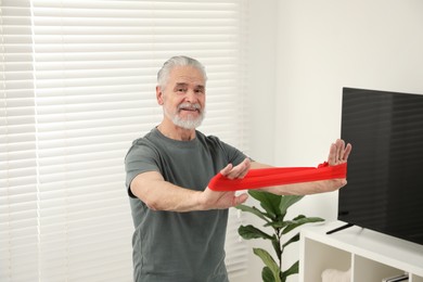 Senior man doing exercise with fitness elastic band at home