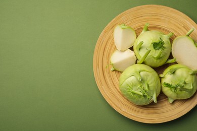Photo of Whole and cut kohlrabi plants on green background, top view. Space for text