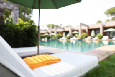 Photo of Sunbeds near swimming pool at luxury resort, blurred view