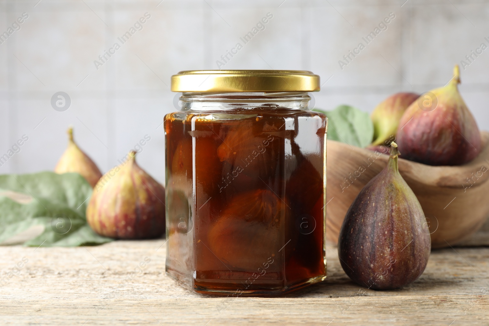 Photo of Jar of tasty sweet jam and fresh figs on wooden table