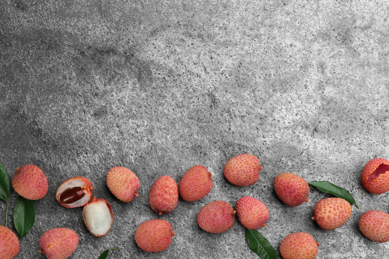 Photo of Fresh ripe lychee fruits on grey table, flat lay. Space for text