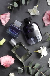 Luxury perfumes and floral decor on black table, flat lay
