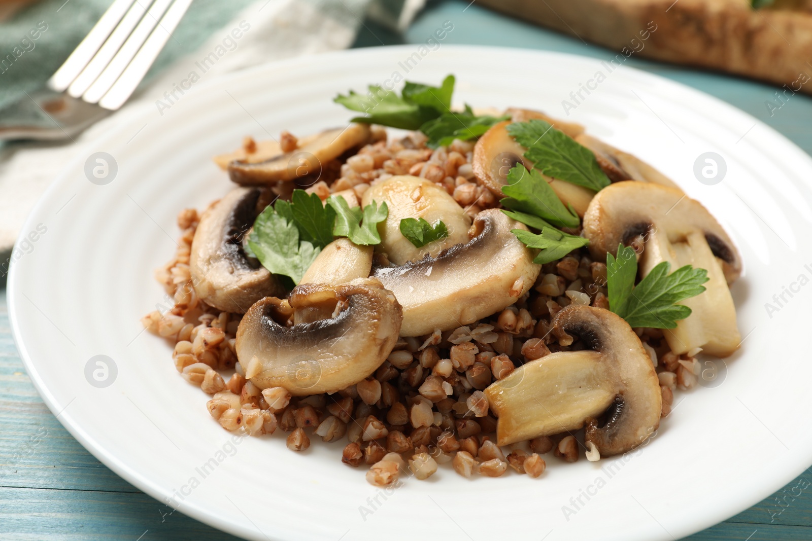Photo of Tasty buckwheat with fresh parsley and mushrooms on table, closeup