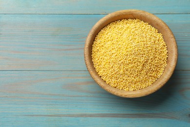 Millet groats in bowl on light blue wooden table, top view. Space for text