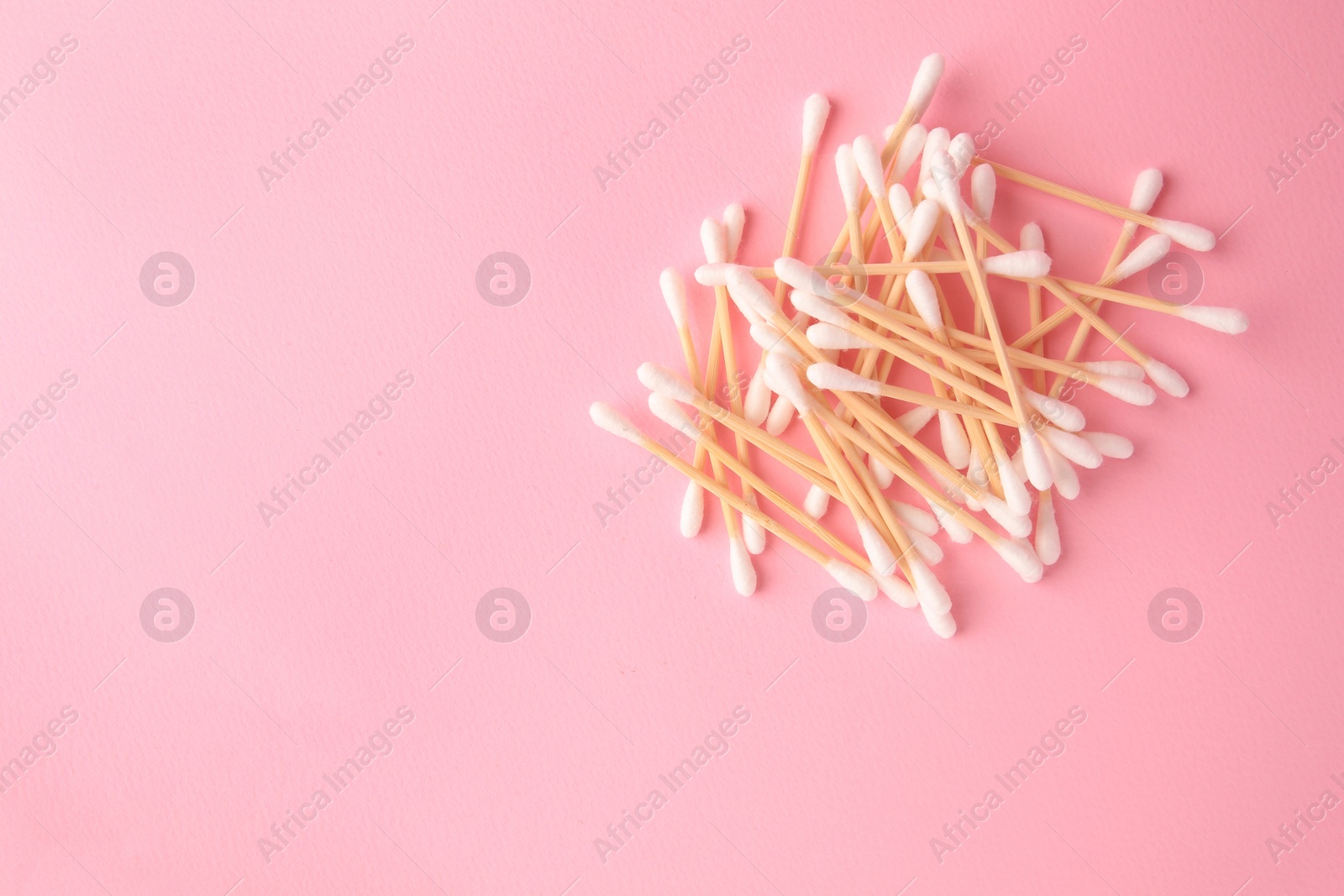 Photo of Heap of clean cotton buds on pink background, flat lay. Space for text