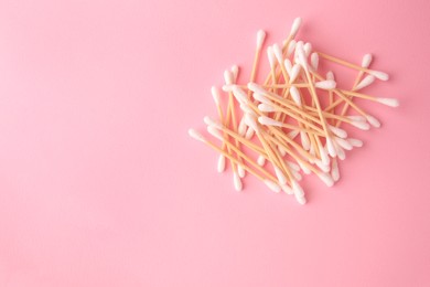 Photo of Heap of clean cotton buds on pink background, flat lay. Space for text