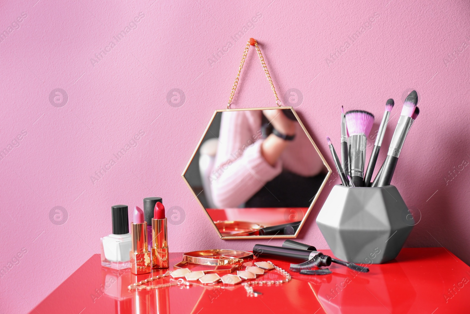 Photo of Modern mirror with makeup products and accessories on color background