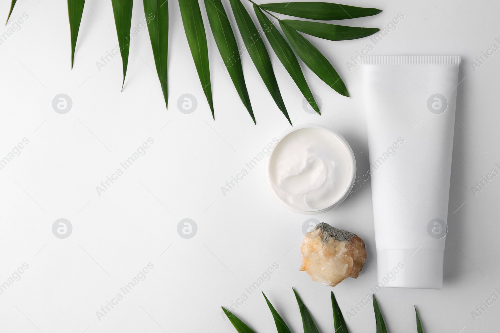 Photo of Cosmetic products, quartz gemstone and palm leaves on white background, flat lay. Space for text
