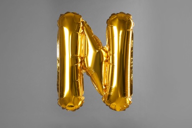 Photo of Golden letter N balloon on grey background