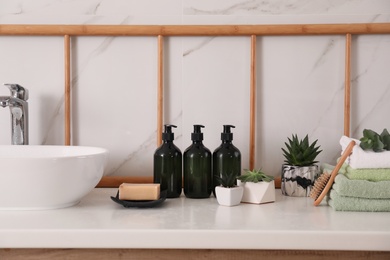 Soap dispensers, towels and plants on countertop in bathroom