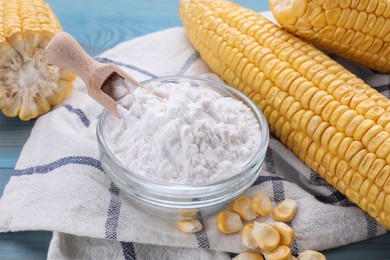 Bowl with corn starch, ripe cobs and kernels on light blue wooden table