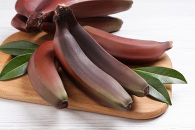 Photo of Tasty red baby bananas on white table, closeup