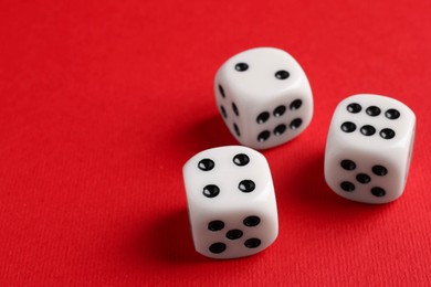 Photo of Three white game dices on red background, closeup