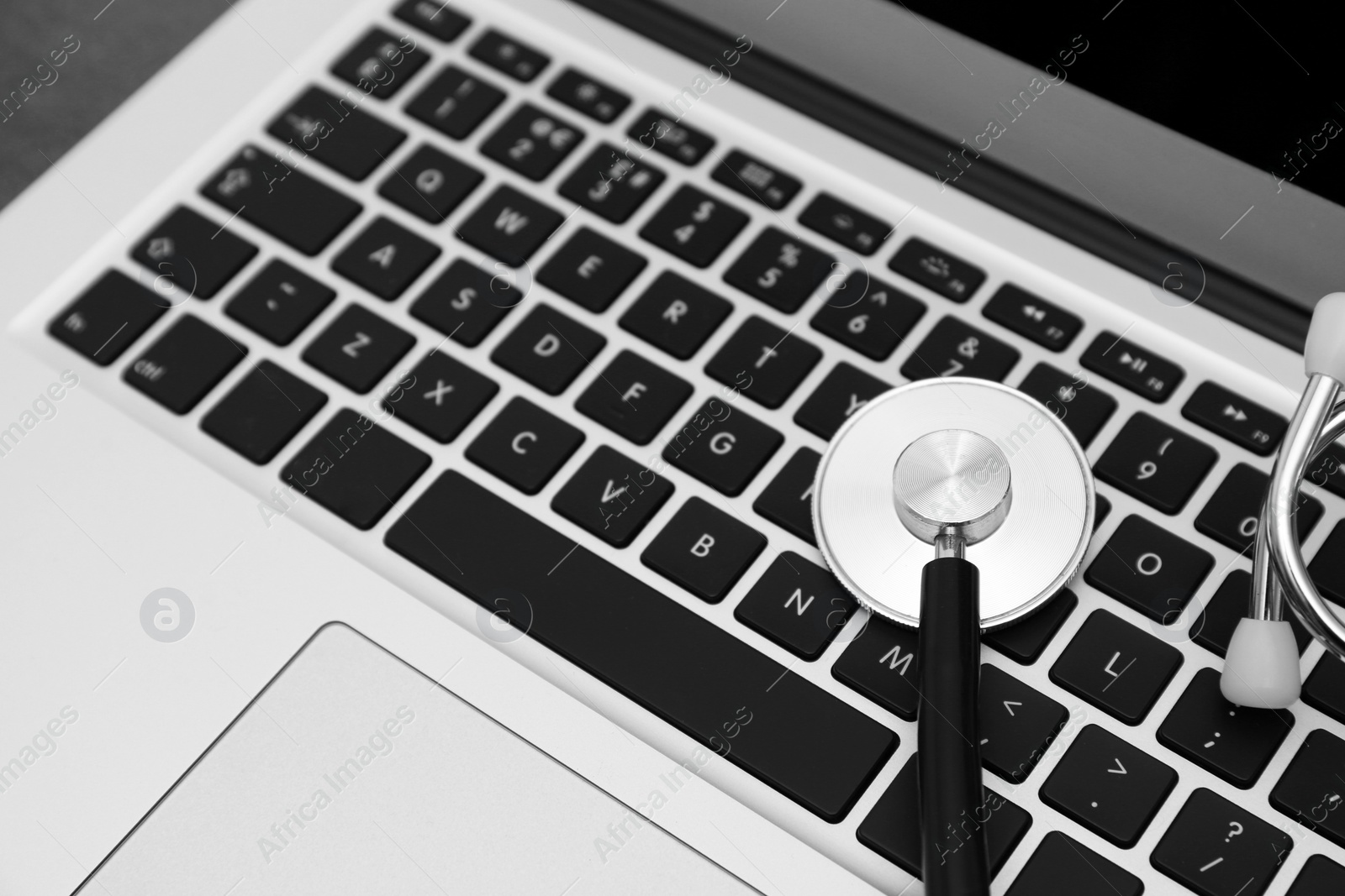 Photo of Modern laptop and stethoscope, closeup. Technical support concept