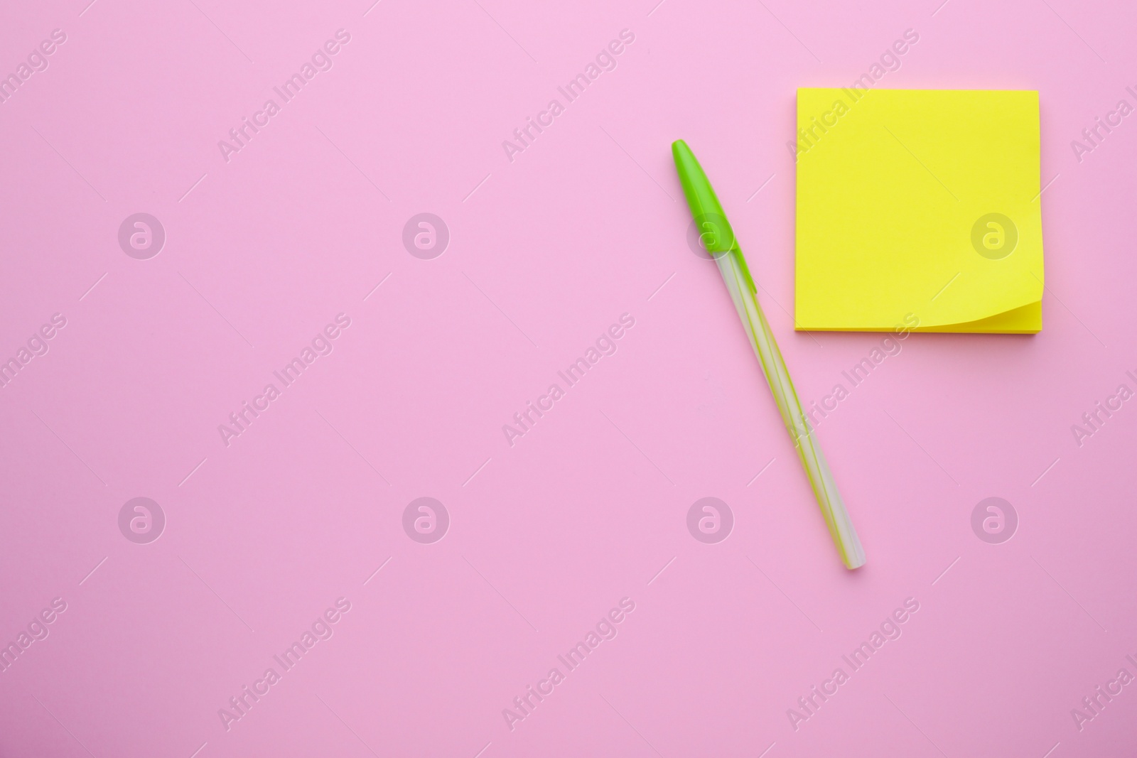 Photo of Paper note and pen on pale pink background, flat lay. Space for text