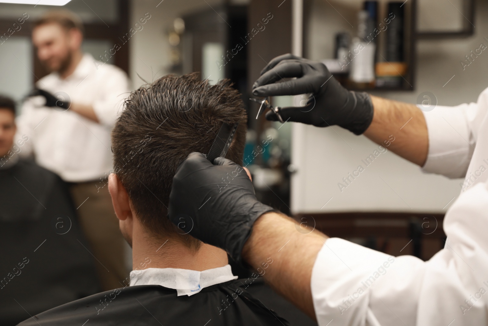 Photo of Professional hairdresser making stylish haircut in salon, closeup